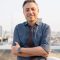 happy-mature-handsome-businessman-smiling-with-arm-2021-08-27-18-01-49-utc-Custom-e1643051599503.jpg